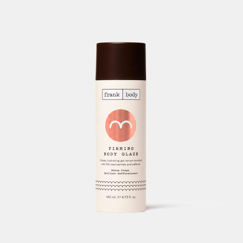 A tall cream-coloured bottle of frank body Firming Body Glaze with a dark brown cap and coral-pink logo, standing on a light grey background.