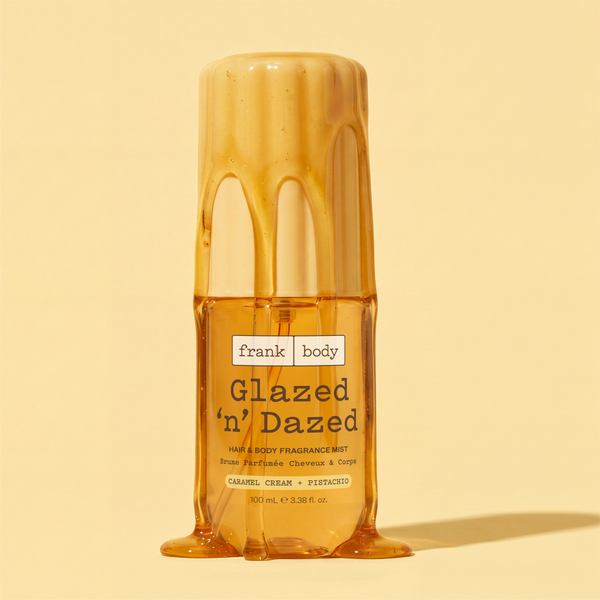 A yellow bottle of frank body On-the-Go Glazed 'n' Dazed Hair & Body Fragrance Mist on a yellow background.
