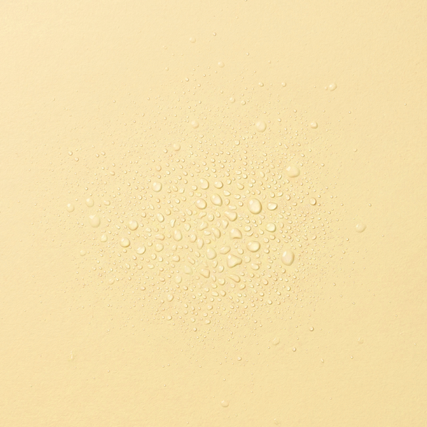 Droplets of frank body Glazed 'n' Dazed Hair & Body Fragrance Mist on a yellow background.