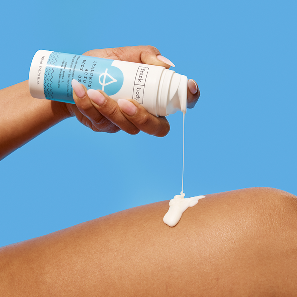A hand dispensing frank body Hyaluronic Acid Body Serum onto a leg.