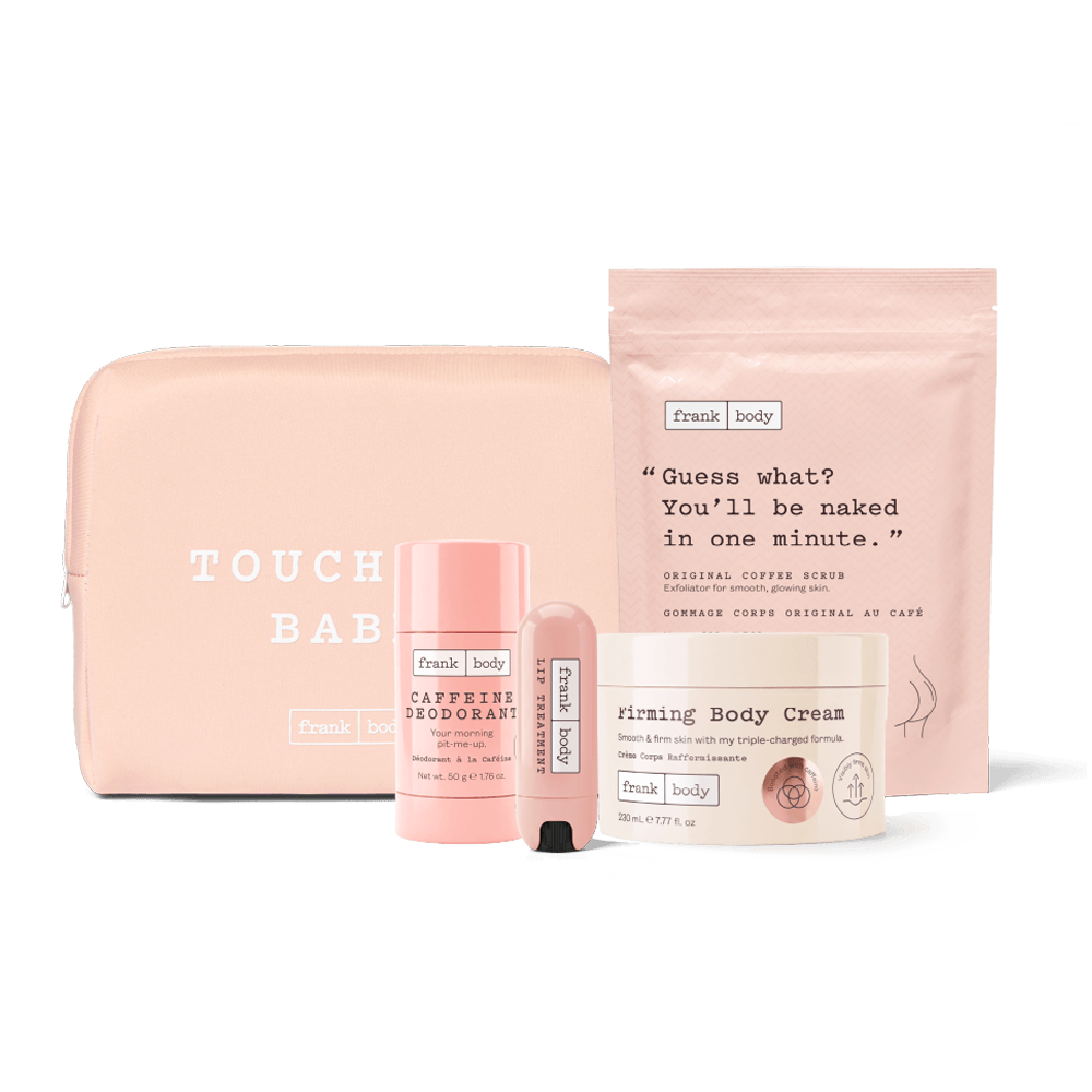 A Frank Body gift set featuring a blush pink zippered pouch, a deodorant stick, a body cream tube, and a body scrub packet, all arranged on a light gray background.