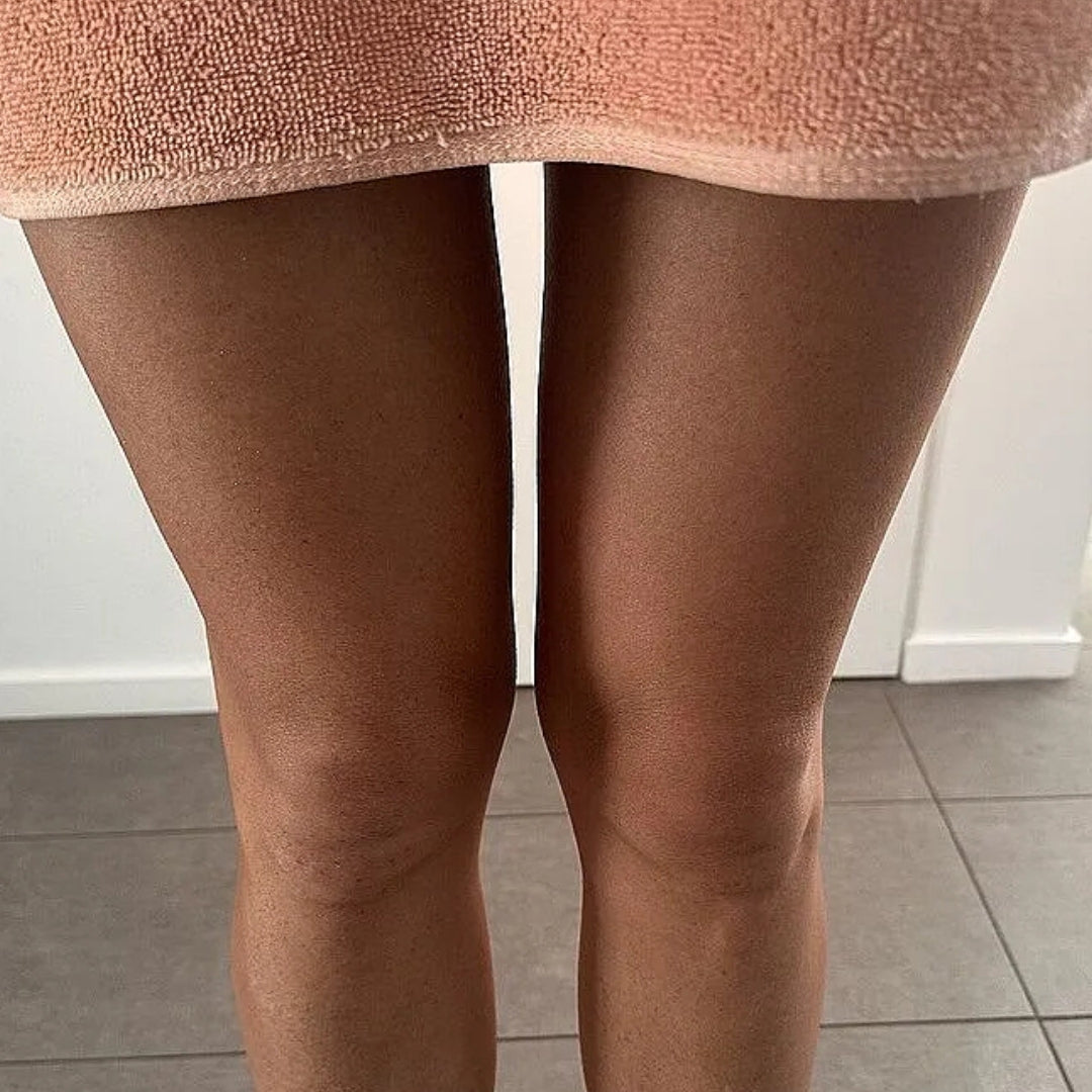 Close-up of a person's tanned legs, showing the after result of using the frank body self tan mousse.